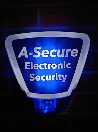 An illuminated A-Secure bell box glowing blue on a building at night
